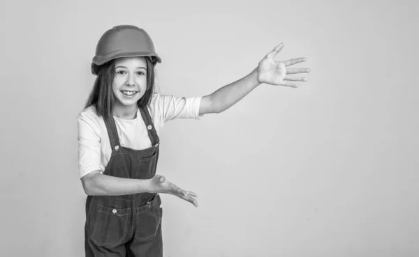 Menina criança em chapéu duro no local de construção, apresentando o produto, espaço de cópia para propaganda — Fotografia de Stock