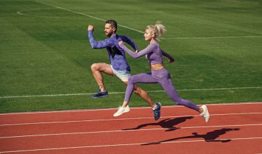 Ne pahasına olursa olsun başarı. Fitness çifti dışarıda antrenman yapıyor. Koşu pistinde koşucular. Meydan okuma ve rekabet. Dayanıklılık. Enerji dayanıklılığı. Zıplayan sporcu tipler. Erkek ve kadın spor eğitmeni koşar