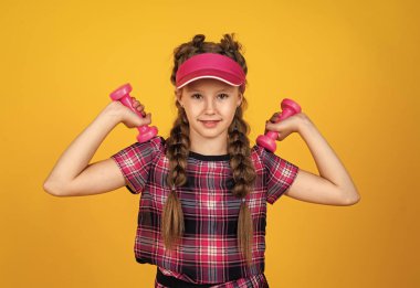 Güçlü ol. Genç kız eğitimi. Fitness 'e adanmıştır. Spor aletleri ve ekipmanlar. Sağlıklı ve aktif bir yaşam tarzı. Enerji dolu. Mutlu çocukluk. Şapkalı çocuk halterleri tutuyor. Dambılı çocuk