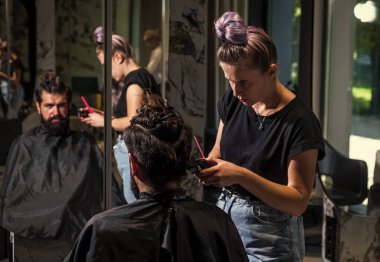 Adam, berber dükkanında saç kesiminde siyah saçlı, beyaz tenli bir adam.