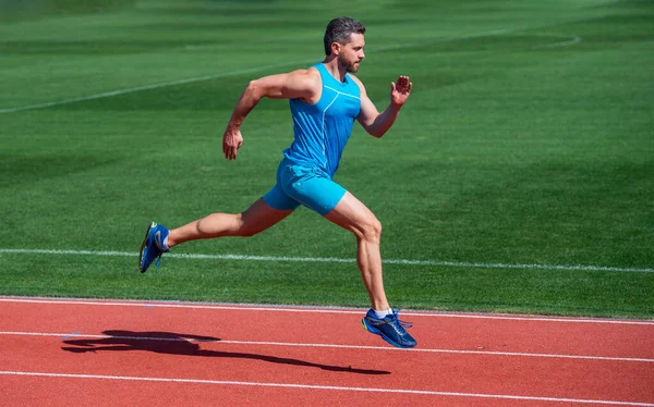 Atlético musculoso hombre corriendo en ropa deportiva en pista de estadio, resistencia — Foto de Stock