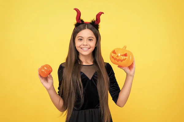 Wees zo lief. kind in imp horens met jack o lantaarn. Een kind draagt duivelshoorns met pompoen. najaarsvakantie. grappig tienermeisje klaar om feest te vieren. Kostuum feestje leuk. gelukkig Halloween — Stockfoto