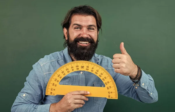 mature bearded man teacher in school classroom with blackboard, math