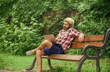 Çalış ve rahatla. İnternette çalışıyorum. Hippi parkta ilham kaynağı oldu. Çevik iş. Sakallı adam yedek kulübesinde oturuyor. Modern laptop. Uzaktan kumanda. Temiz hava. Gezici internet. İnternetten alışveriş