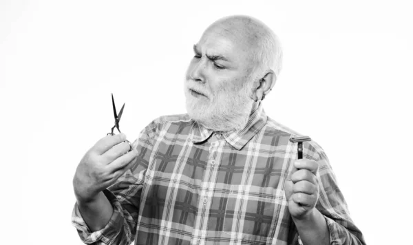 Homem maduro barbeiro segurar tesoura e lâmina de barbear no fundo branco. A aparar barba e bigode. Serviço de arrumação. Cabelo facial de barba cortada. Cortar ou barbear. Escolha o comprimento perfeito e a forma da barba — Fotografia de Stock