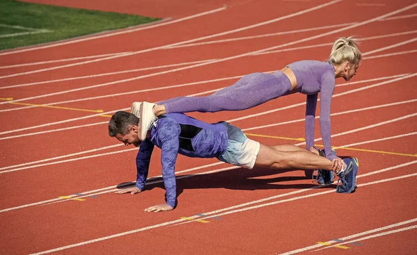Deporte fitness hombre y mujer entrenando juntos de pie en tablón y empujar hacia arriba en pista de carreras de estadio al aire libre con ropa deportiva, estilo de vida saludable — Foto de Stock