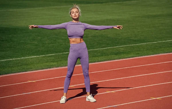 Sexy sportliche Dame dehnt und wärmt sich in Sportbekleidung auf Stadionlaufbahn, gesunder Lebensstil — Stockfoto