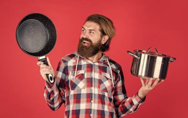 Havalı, bakımlı, sakallı, tavayla yemek pişiren, yemek pişiren bir hippi.