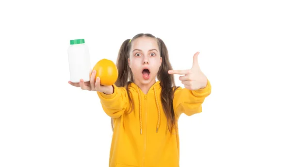 Criança apontando o dedo na fruta laranja e pílula vitamínica em frasco isolado em branco, surpresa. — Fotografia de Stock