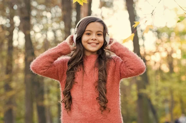 Šťastný kluk relaxovat v podzimní přírodě. Holčička nosí sluchátka. moderní školní vzdělání. dítě poslouchat hudbu v podzimním lese. užijte si elearning ve sluchátkách. dítě nosit svetr v podzimním parku — Stock fotografie