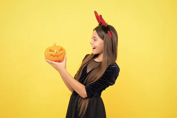 Bom para comer. Festa de fantasia divertida. Feliz Dia das Bruxas. criança em chifres imp com jack o lanterna. O miúdo usa chifres de diabo, segura a abóbora. férias de outono de infância. engraçado adolescente menina pronto para celebrar a festa — Fotografia de Stock