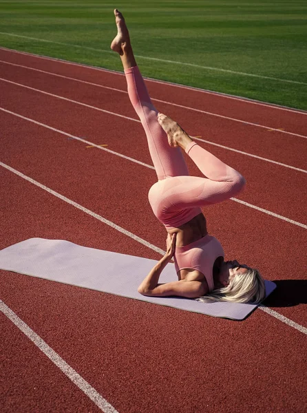 Spor giyim ve jimnastik konusunda esnek bir kadın stadyumda geriniyor. — Stok fotoğraf