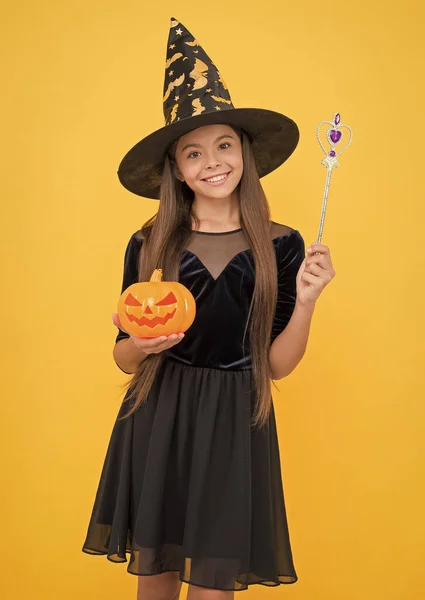 Criança bruxa feliz com varinha mágica e macaco de abóbora o lanterna usar traje de feiticeiro na festa de Halloween, milagre de Halloween — Fotografia de Stock