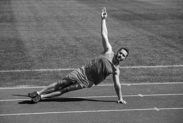 Musculoso hombre de pie en la tabla lateral estiramiento en el entrenamiento deportivo, yoga — Foto de Stock