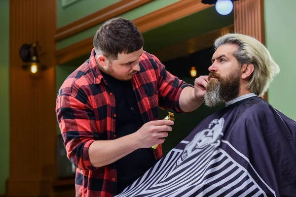 Prueba cosas diferentes. hipster en la barbería. cliente barbudo visitando peluquería. Hora de un nuevo corte de pelo. El hombre mira el reflejo del espejo. hombre guapo maduro con el pelo largo. peluquero o peluquero — Foto de Stock