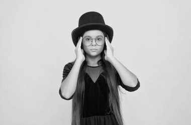 İhtiyacın olan tek şey değişim. Küçük kızın modaya uygun görünüşü. Küçük çocuk sarı arka plandaki gözlüklere bakar. Güzellik salonu. Moda bir aksesuar. Kıyafetler ve parti kıyafetleri.