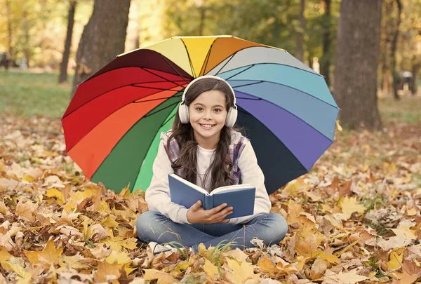 Audio learning in any weather. Small girl listen to audio book on autumn landscape. Little child enjoy audio learning outdoor. Audio players and talking books. Audiobook