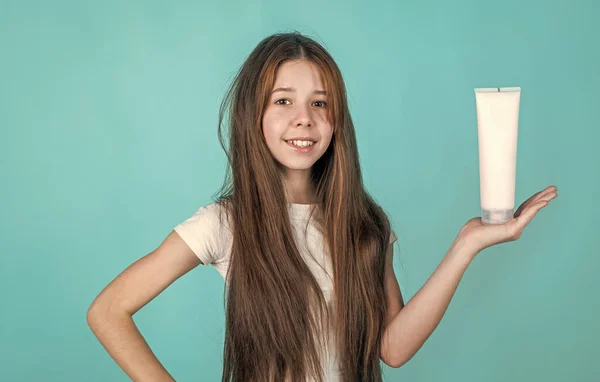 Lavar e enxaguar. menina adolescente feliz apresentando produto cosmético. shampooing cabelo no salão. hábitos diários e cuidados pessoais. criança use xampu creme em garrafa. condicionador de cabelo. beleza máscara nutritiva — Fotografia de Stock