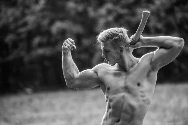力量和力量的概念。英俊无袖男人肌肉发达的身体用斧头砍树性感男子赤身裸体。在野外生存。森林里的肌肉运动员运动和健身。肌肉体 — 图库照片