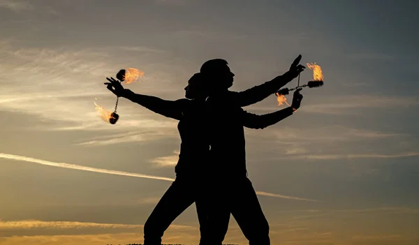 Tänd din dansande låga. Dansande par snurrar brinnande poi. Flamdansare på idyllisk himmel. Kväll nyanser och ljus. Eldgivning. Utomhusfestival. Nattfest. Kul och underhållning — Stockfoto