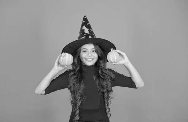 Enfant heureux en costume de chapeau de sorcière à Halloween avec petite citrouille jaune, nourriture d'Halloween — Photo