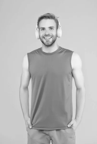 Homme barbu souriant écouter de la musique dans les écouteurs numériques portant des vêtements sportifs pour l'entraînement, la formation — Photo