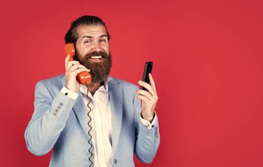 Teknoloji gelişimi kavramı. O zaman ve şimdi. Olgun sakallı adam retro telefonda konuşuyor. Erkek, akıllı telefonu tutar. Teknolojiyi. Cep telefonuna karşı retro telefon. İş görüşmesi. Sonuçlara adanmış