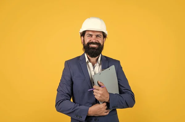 Architecture et bâtiment. constructeur masculin portant costume formel et casque pour la protection. travailler sur un projet de construction. homme souriant avec barbe porter un casque dur. concept d'ingénierie — Photo