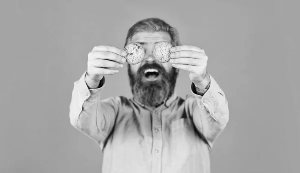 Um homem a comer bolachas de chocolate. cheia de calorias. conceito de alimentos nocivos. pastelaria e sobremesa. anúncio de loja de padaria. homem em dieta. hipster barbudo segurar biscoito. Natal símbolos doces — Fotografia de Stock