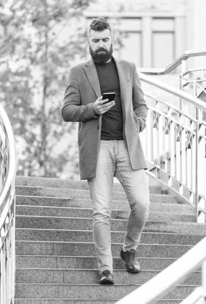 Komunikacja jest kluczem do sukcesu zawodowego. Brodaty człowiek czyta smsy w smartfonie spacerując po mieście na zewnątrz. Komunikacja biznesowa. 3G. 4G. Technologia mobilna. Nowoczesny styl życia — Zdjęcie stockowe