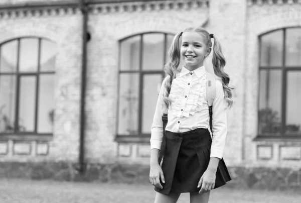 Criança feliz com caudas de cabelo comprido de volta à escola vestindo uniforme de moda no pátio da escola ao ar livre, 1 de setembro — Fotografia de Stock