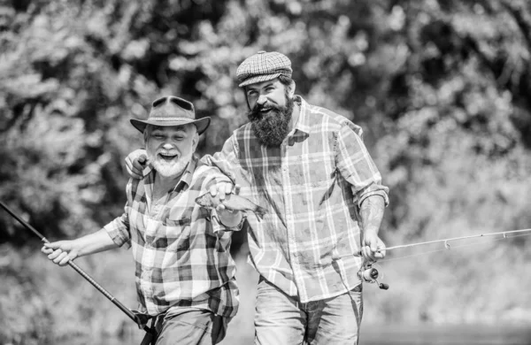 Pesca de caza mayor. amistad. turismo de caza. padre e hijo pescando. dos pescador feliz con caña de pescar y red. Acampar en la orilla del lago. concepto de una escapada rural. hobby. Tiempo de pesca con mosca —  Fotos de Stock