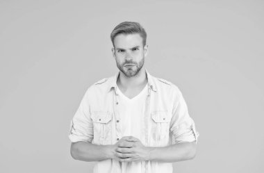 Seksi tüylü ciddi bir adam sarı arka planda günlük gömlek giyer, kendine güvenir.