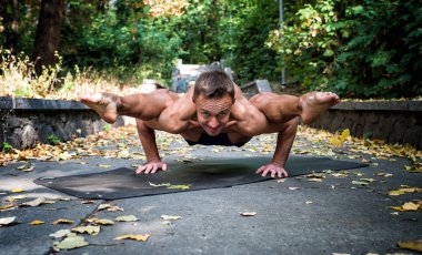Yakışıklı atletik adam parkta yoga yapıyor.
