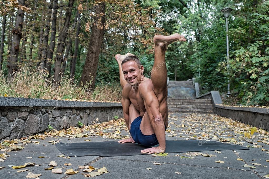 Handsome smiling flexible Athletic man doing yoga asanas in the Stock Photo  by ©stetsik 66985233