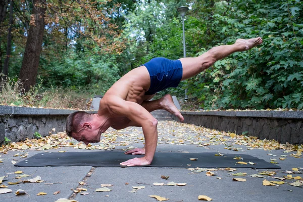 Handsome smiling flexible Athletic man doing yoga asanas in the — Stock Photo, Image