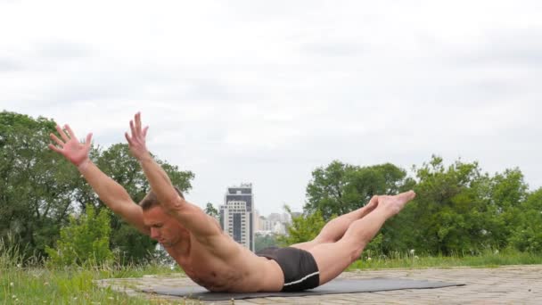 Bel homme flexible athlétique faire des asanas de yoga dans le parc — Video