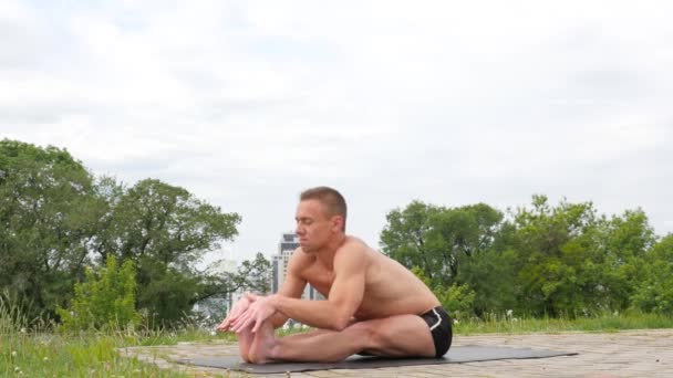 Stilig flexibla atletisk man gör yoga asanas i parken — Stockvideo