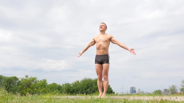 Knappe flexibele atletische man doen yoga asana's in het park — Stockvideo