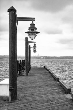 Sokak lambasıyla deniz kenarında gezinti. Rıhtımdaki iskele yolunda kimse yok. Deniz ufku. İskele güvertesi, deniz manzaralı sokak lambası. Soğuk hava.