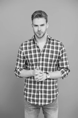 Gündelik giyinen milenyum adamı. Erkek güzeli. Yakışıklı genç adam. Sıradan gömlekli bir adamın portresi. Gri üzerinde kollarını çapraz tutuyor. Tıraşsız erkek derisi. Erkek güzelliği ve saç stili.