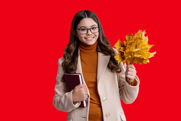 Autumn leaves. Fall fashion girl. Autumn teen girl wearing coat and looks stylish. Fall season. Autumnal girl in autumn fall. Autumn mood of adolescent model isolated on red. Autumnal scenery.