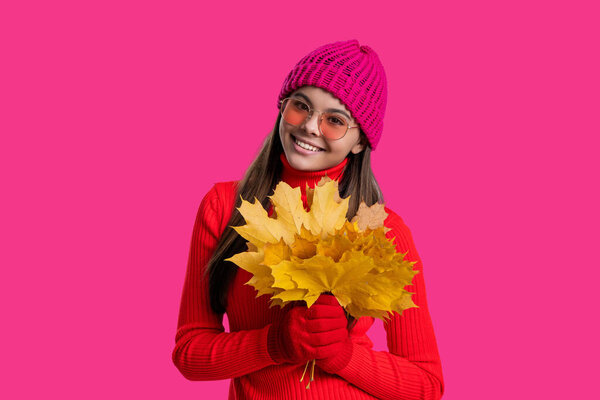 Autumnal season. Fall fashion. Happy young girl playfully hold yellow maple leaves. Teen girl with fallen leaves isolated on pink. Autumn girl hold fallen leaves. Fall and autumn. Seasonal mood.