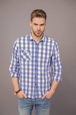 Tıraşsız adamın zarif portresi. Gri yolda izole edilmiş bir adam. Kareli gömlek giyen milenyum adamı. Milenyum erkeğinin gündelik tarzı. Sıradan tişörtlü bir adamın portresi. Çabasız bir şekilde şık..