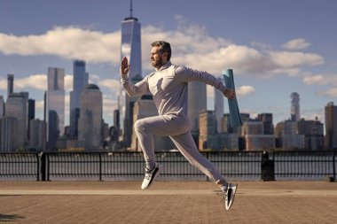 Sporcu sporcu, New York 'ta sabah sporu için spor minderiyle koşuyor.