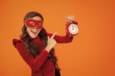 Parti maskeli neşeli genç kız saati işaret ediyor. Parti sonrası eve geç gelen bir kız. Tatil eğlencesi bitti. Geri sayım. Geç kalan kız turuncudan izole edilmiş. Geç saatte. Parti geri sayımı.