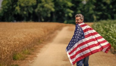 4 Temmuz. Amerikan İşçi Bayramı. Amerikan bayrağı ve çiftçi adam. ABD bayrağı. Bağımsızlık Günü. Sahadaki adam. Ekin tarlasında Amerikan bayrağı taşıyan adam. Amerika 'nın Bağımsızlık Günü. Boşluk afişini kopyala.