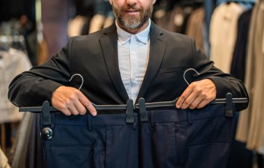 Retail assistant help stylish man find suit. Stylish man in suit. Businessman choose elegant suit in store. Trendy suit. Hispanic businessman choosing tailoring, cropped. Bespoke tailoring.