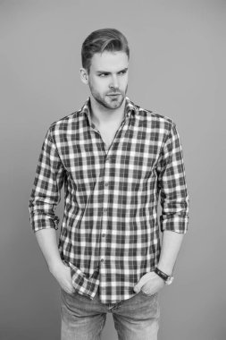 Yakışıklı genç adam. Sıradan gömlekli bir adamın portresi. Gri üzerinde kollarını çapraz tutuyor. Tıraşsız erkek derisi. Erkek güzelliği ve saç stili. Gündelik giyinen milenyum adamı. Moda eklentisi.