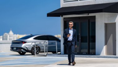 Businessman using smartphone. Successful businessman chatting online. Businessman walking. Corporate business. Business man chat on phone outdoor. Businessman chatting on phone in parking.